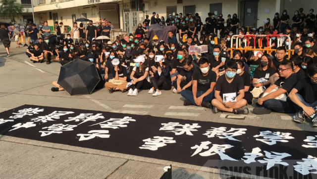 不滿警方開實彈，市民、校友在校外靜坐聲援中槍學生。(翻攝香港電台網站)