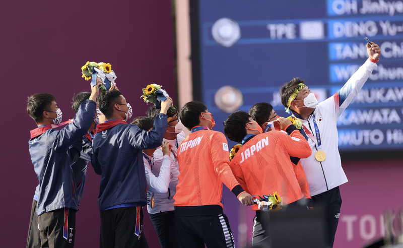 射箭男子團體賽，金銀銅牌分別由韓國（白衣）、台灣（藍衣）及日本（橘衣）拿下。頒獎典禮後，韓國隊提議3隊選手一起自拍留念。（中央社）